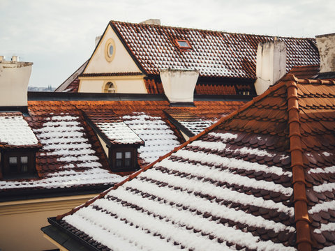 Red old tile roofs of houses with snow