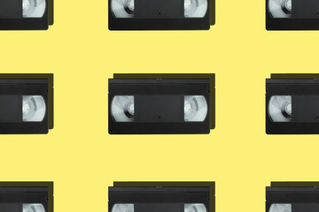 Seamless pattern with retro vhs tapes flat lay on colorful yellow background top view. Creative...