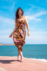 Fototapeta na wymiar Lifestyle, a brunette girl walking in a hat and a black floral dress
