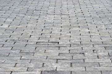 The sidewalk is made of rectangular gray granite bricks . Background