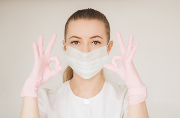 Girl in medical gloves dress a medical mask on her face on a light  background. Respiratory disease. Covid-19