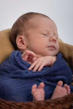 Close Up Portrait Of Infant Small Baby Wrapped In Blue Fabric Sleeping In Basket 