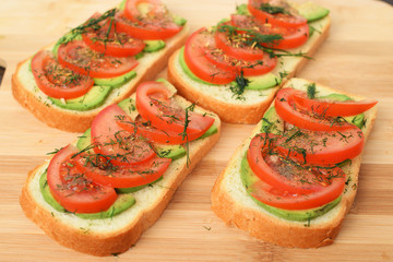 sandwiches with fresh avocados, tomatoes and greens on wooden Board background. side view