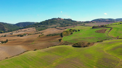 Fototapeta na wymiar Italian village of Monticchiello in Tuscany, Italy. Drone flying over the magnificent village and green meadows. Perfect for authentic travelling in Italy 