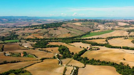 Italian field all over the horizon with agricultural fields and meadows Aerial view of the beautiful  old village of Monticchiello Tuscany, Italy