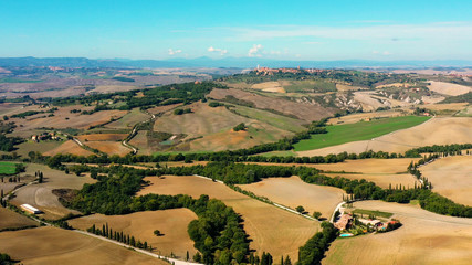 Italian field all over the horizon with agricultural fields and meadows Aerial view of the beautiful  old village of Monticchiello Tuscany, Italy