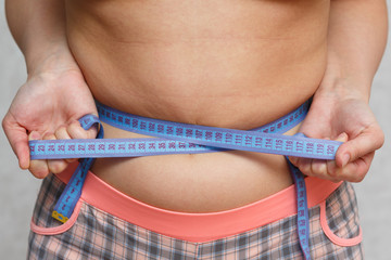 the girl pulls the stomach measuring tape. the concept of weight loss