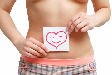 Women Health. Closeup Of Healthy Female With Beautiful Fit Slim Body Holding White Card With Happy Smiley Face heart shaped In Hands. Stomach Health And Good Digestion Concepts. High Resolution