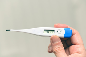 hand holding a thermometer with a high fever temperature of more than 40 celsius
