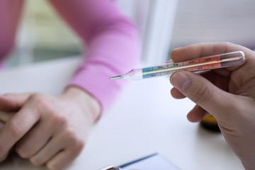 Closeup shot of a woman looking at thermometer.