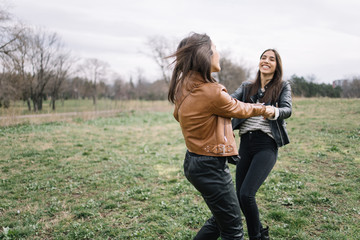 Two happy girls spinning together in nature