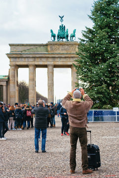Man taking photo Brandenburg Gate Building and Christmas Tree Berlin