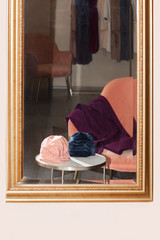 Fototapeta na wymiar 2 hats on the table and a coat on the sofa in hotel through the mirror