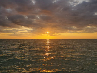 Abstract seascape panoramic background - Orange color in the sky, sunset late afternoon. Calm seas/ocean in the bottom of the frame. Minimalistic simple background image, blue and yellow colors.