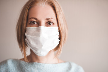 Adult woman wearing medical mask closeup. Looking at camera. Home quarantine. European.