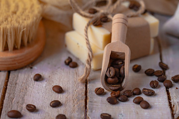 Concept of home natural organic skin care. Handmade soap bars with coffee used as gentle scrub. Brush to increase anti-cellulite effect. Relax pleasant treatement. Wooden background close up