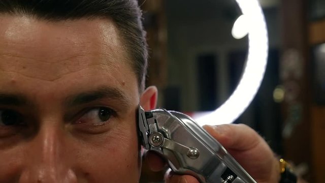 Male hairstyle with electric shaver in barber shop.