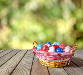Fototapeta na wymiar Painted Easter eggs in basket on wooden table
