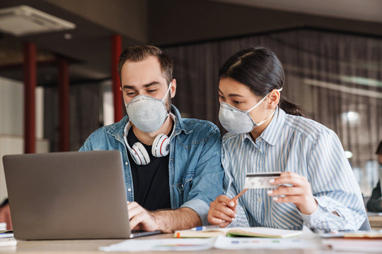 Photo of students in medical masks holding credit card while studying