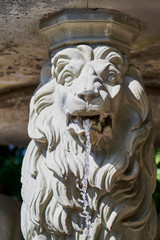 Naklejka premium A fountain made of wite stone in the shape of a lion, water springing from the lion's mouth.