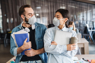Photo of multinational students in medical masks standing at classroom