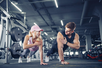 Man and woman strengthen hands at fitness training. Fitness young people doing pushups in a gym looking face happy exercise