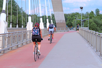 Cyclists ride bicycles on bridge in Warsaw. Tourists travel by bike