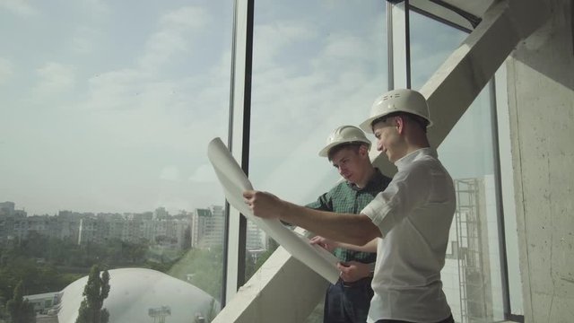 Two young architects verify the execution of the construction work in an office building