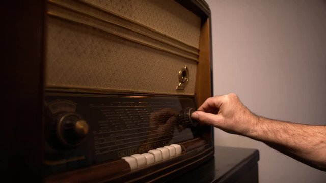 Man hand searching for the radio station on the vintage radio