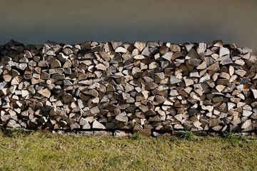 Carefully arranged pieces of firewood next to wall