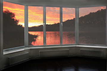 Plastic window overlooking beautiful crimson sunset above river