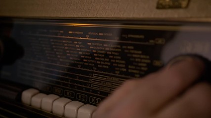 Close up, elderly man hand Tuning FM radio stations on vintage receiver dial, racking focus