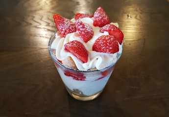 Whipped cream dessert and slices of fresh strawberries in a large glass