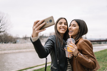 Smiling women with juice cups making selfie