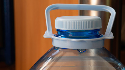 Five liter bottle - close up. Plastic container with water. Blue plastic bottle stopper.
