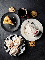 Different desserts with coffee on black background, top view.
