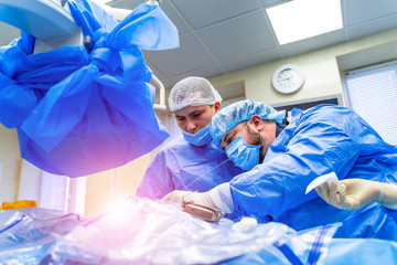 Operating Room With Surgery In Progress. Medical team performing surgical operation in bright...