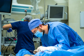 Group of doctors perform an operation to a patient. Surgeons in medical uniform and masks working in the operating room