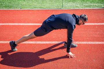 Athletes walk and stretch on the red wet track of athletics, which is a rubber artificial track for...