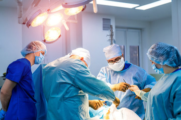 Medical team performing surgical operation in bright modern operating room.