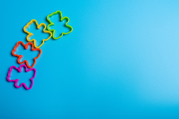 Four multi-colored plastic cookie cutter for making cookies in the shape of a teddy bear on a blue...
