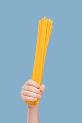 close up, child's hand held spaghetti isolated on blue background, in studio