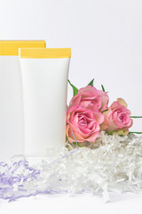 Natural cosmetics SPA mock-up on white background with flowers and soft paper filler. Organic cosmetic packaging cardboard box and plastic tube, Day care cosmetic product concept, vertical