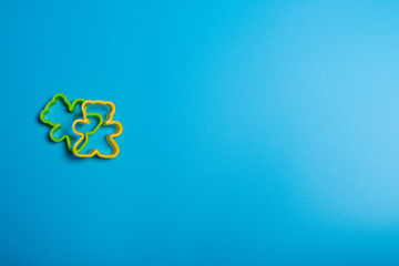Green and yellow plastic cookie cutter for making cookies in the shape of a teddy bear on a blue...