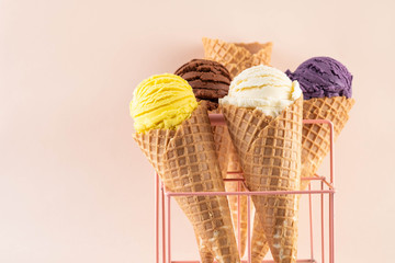 Assorted ice cream in sugar cones on pink background. Copy space.