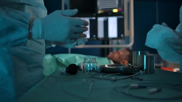 Dark-skinned patient on the operating table against the background of surgeons' hands with professional surgical tools on table.