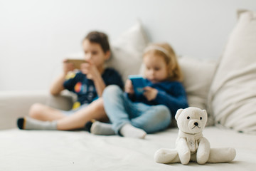 abandoned toy bear on the background of children who play on the phone