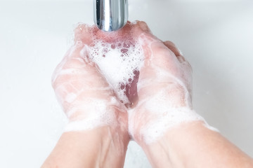 Washing hands with soap under the faucet with water