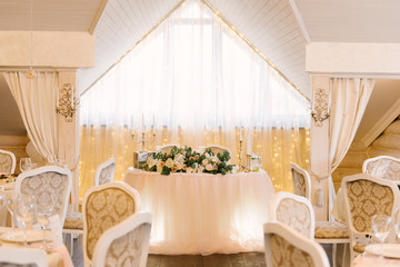 Wedding decor in the restaurant. Beautiful bright podium decorated with flowers.