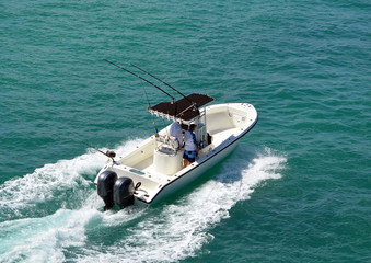 Angled overhead view of an open sport fishing boat with a black canvas canopied center console...
